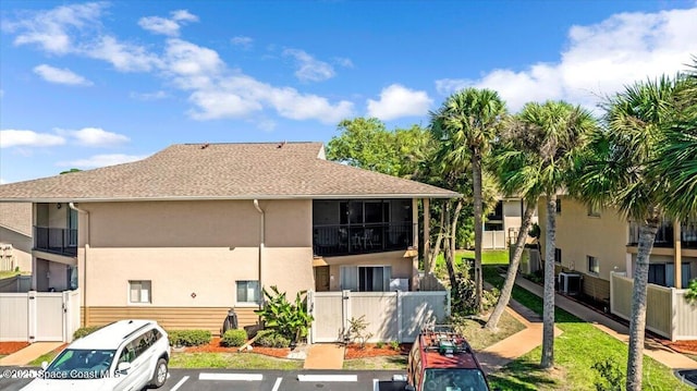 back of property featuring central AC unit, fence private yard, a gate, stucco siding, and uncovered parking