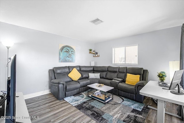 living area with visible vents, baseboards, and wood finished floors