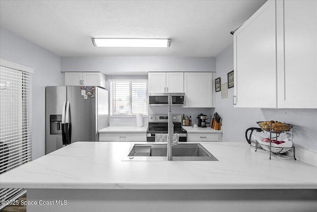 kitchen featuring white cabinetry, stainless steel appliances, and light stone counters