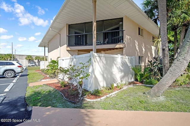 view of side of property with uncovered parking, fence, and stucco siding