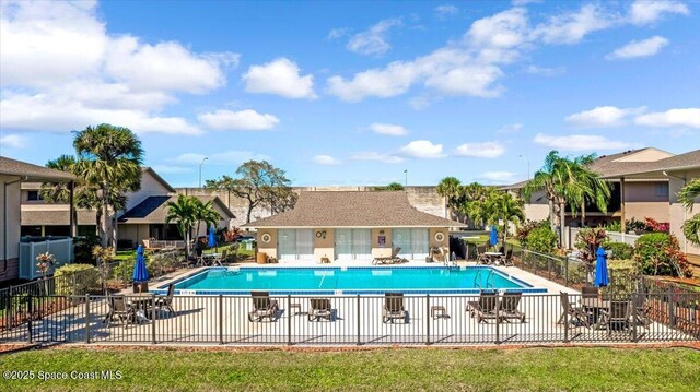 community pool with a patio area and fence