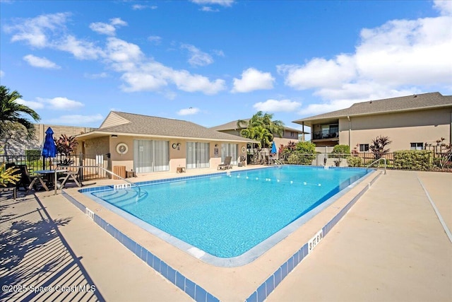 pool with a patio area and fence