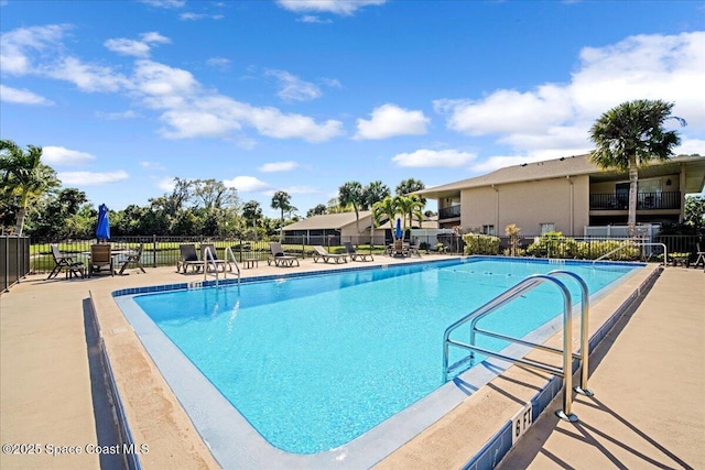 community pool with a patio and fence