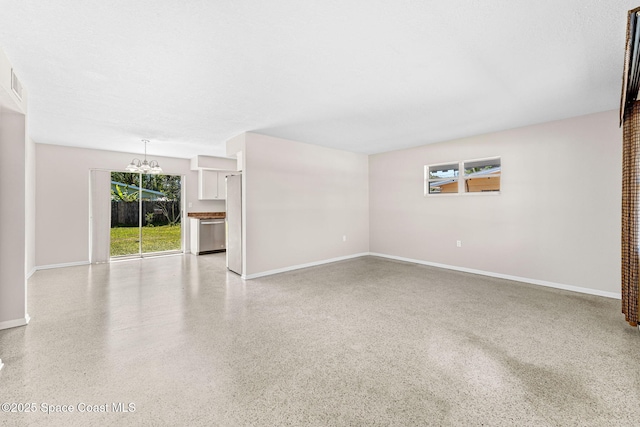 unfurnished living room with baseboards, speckled floor, a textured ceiling, and an inviting chandelier