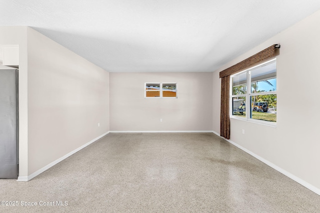 empty room featuring baseboards and speckled floor