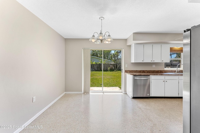 kitchen with dark countertops, appliances with stainless steel finishes, a textured ceiling, white cabinetry, and light speckled floor