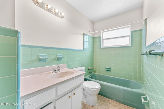 full bath featuring toilet, a wainscoted wall, speckled floor, vanity, and tile walls