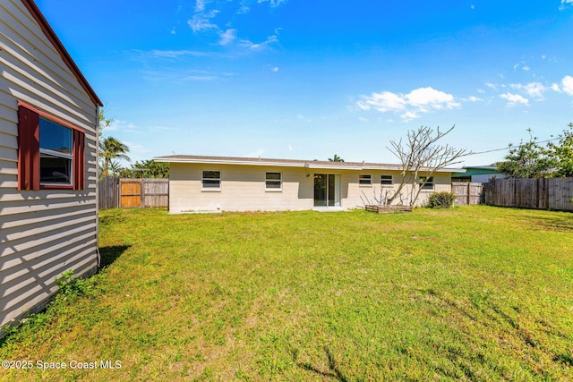 rear view of house featuring a fenced backyard and a lawn