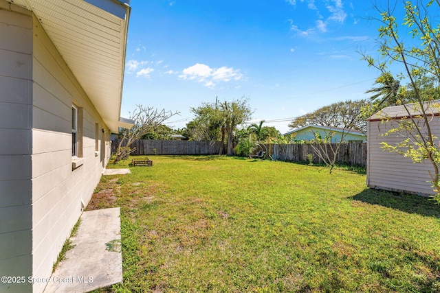 view of yard featuring a storage shed, a fenced backyard, and an outbuilding