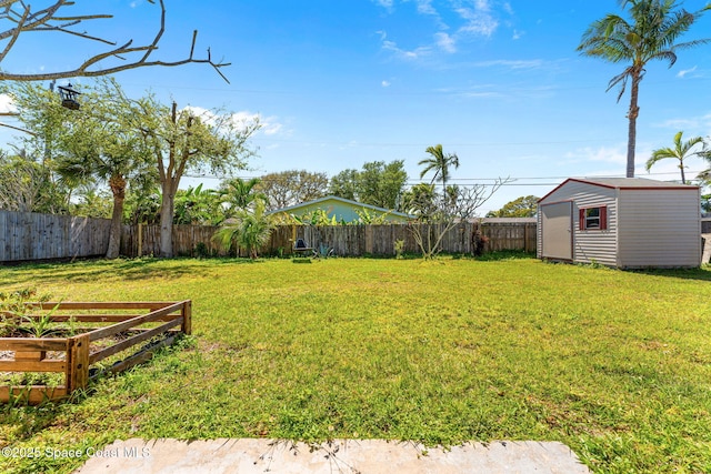 view of yard with an outbuilding, a fenced backyard, and a storage unit