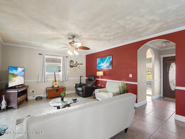 living area featuring tile patterned floors, crown molding, a healthy amount of sunlight, and arched walkways