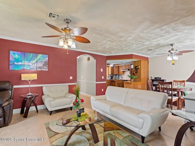 living area with visible vents, baseboards, ornamental molding, light tile patterned flooring, and arched walkways