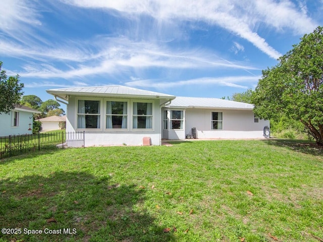 back of house featuring metal roof, a lawn, stucco siding, and fence