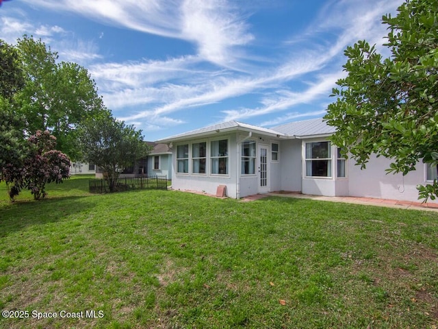 view of front of property featuring metal roof, fence, a front lawn, and stucco siding