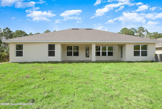 back of property with a shingled roof, a lawn, and stucco siding