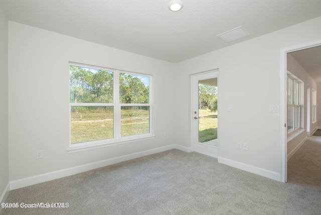 carpeted spare room featuring visible vents and baseboards