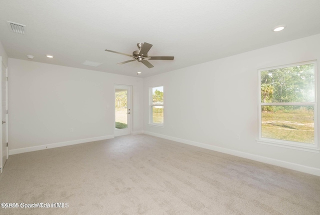 empty room featuring a healthy amount of sunlight, light carpet, baseboards, and recessed lighting