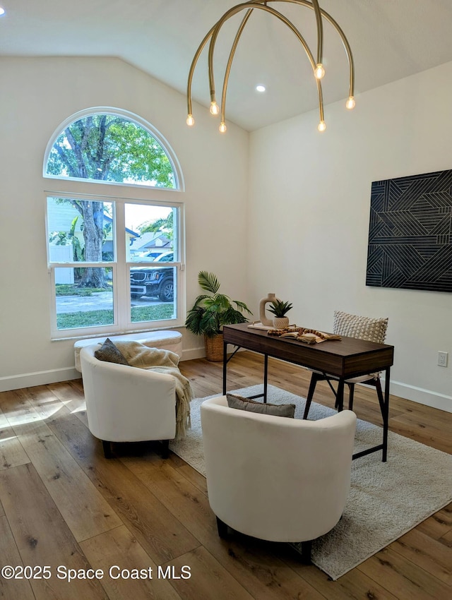 living area with baseboards, lofted ceiling, and hardwood / wood-style flooring