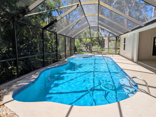 outdoor pool featuring a patio area, glass enclosure, and an in ground hot tub