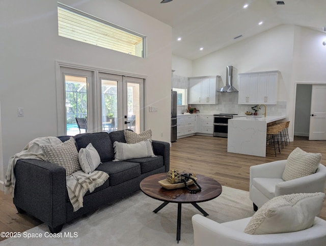 living room with light wood-style flooring, recessed lighting, french doors, and high vaulted ceiling