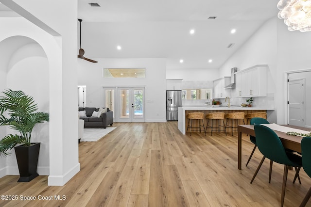 interior space featuring a peninsula, a sink, light countertops, wall chimney range hood, and stainless steel fridge