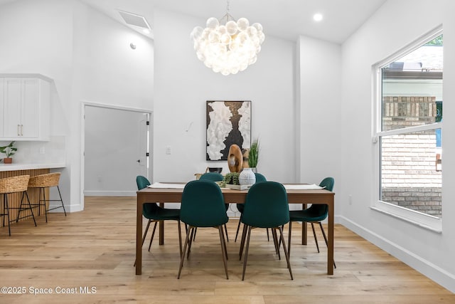 dining area with light wood-style flooring, baseboards, and a chandelier