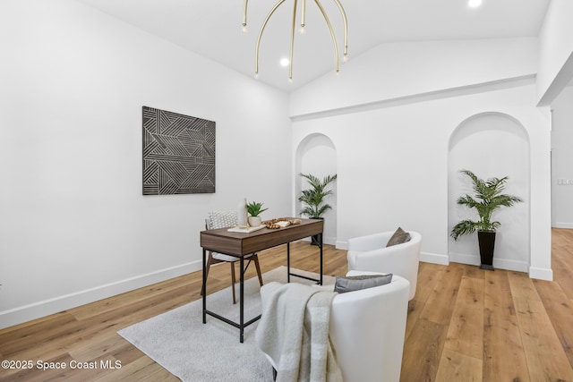 office space featuring arched walkways, light wood-style flooring, baseboards, and lofted ceiling