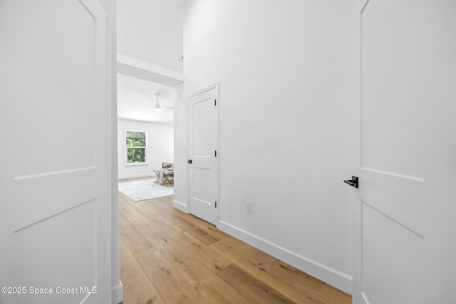 corridor with baseboards and light wood-style floors