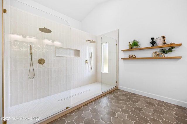 full bathroom featuring tile patterned floors, a walk in shower, baseboards, and vaulted ceiling
