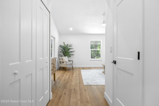 corridor with baseboards and light wood-style floors