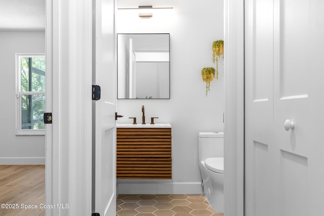 bathroom featuring baseboards, toilet, and vanity