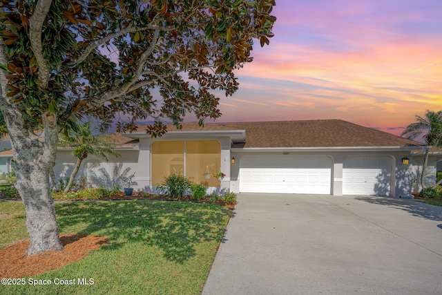 view of front of home with a garage, driveway, roof with shingles, stucco siding, and a front lawn