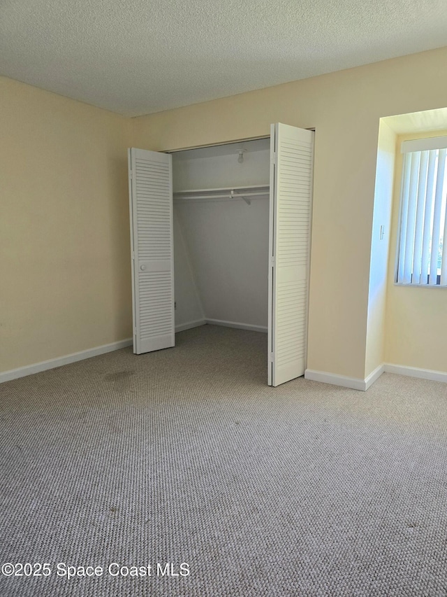 unfurnished bedroom featuring a closet, light colored carpet, and baseboards