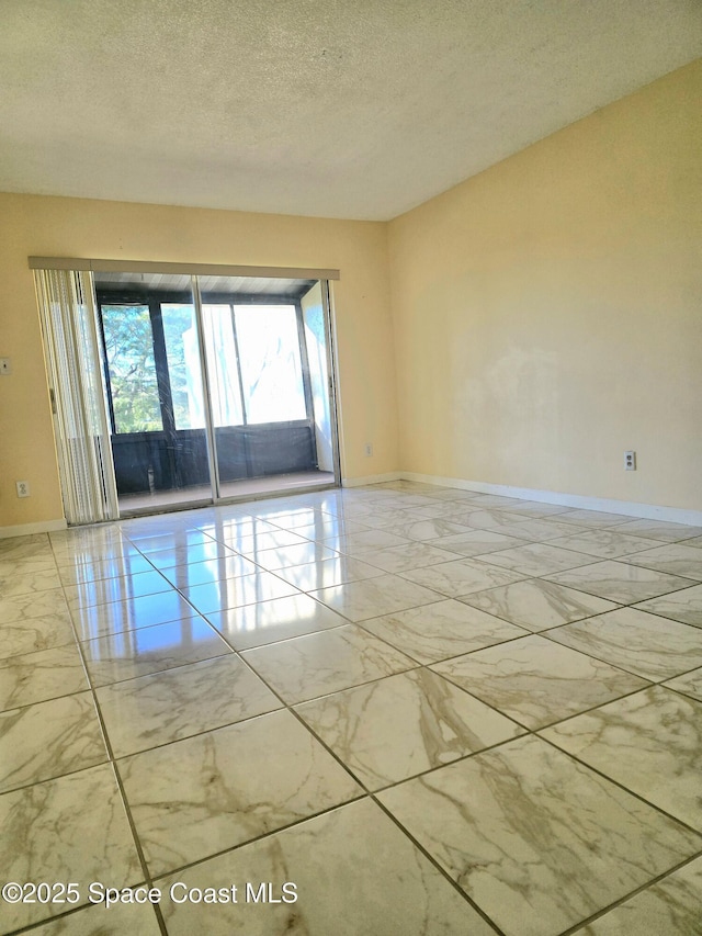 empty room featuring marble finish floor, a textured ceiling, and baseboards