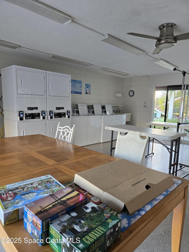 dining room with stacked washer / dryer, ceiling fan, concrete block wall, and a textured ceiling