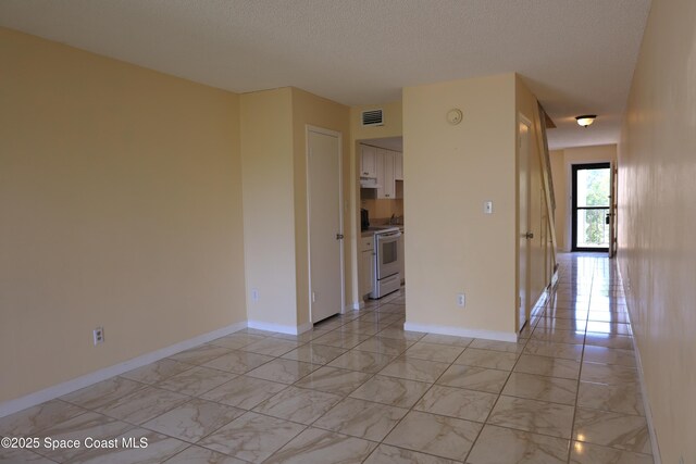 empty room featuring a textured ceiling, marble finish floor, visible vents, and baseboards