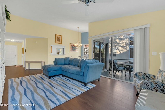 living area featuring ceiling fan with notable chandelier and dark wood-type flooring