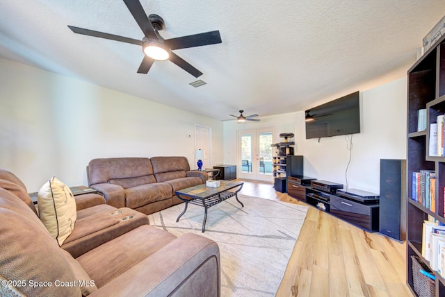 living area featuring french doors, visible vents, a textured ceiling, and wood finished floors