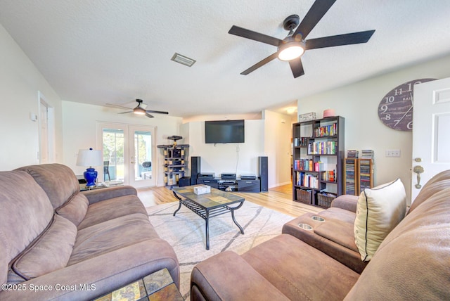 living room featuring ceiling fan, a textured ceiling, visible vents, french doors, and light wood finished floors