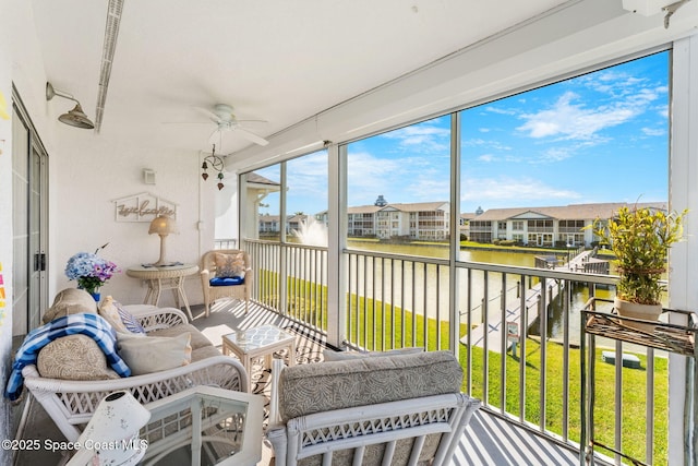 sunroom featuring a ceiling fan, a residential view, and a water view