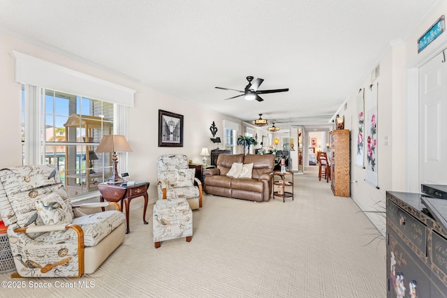 living area with light colored carpet, ceiling fan, and crown molding