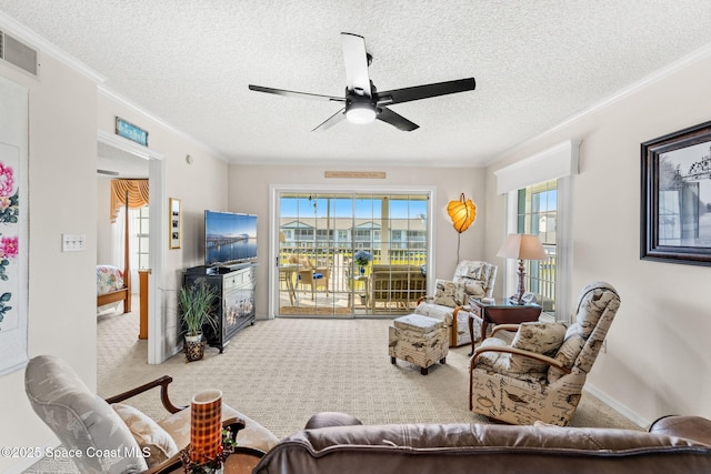 living area with a wealth of natural light, visible vents, carpet floors, and ornamental molding