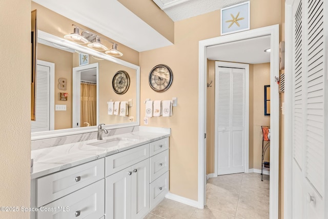 full bath with vanity, tile patterned floors, baseboards, and a closet