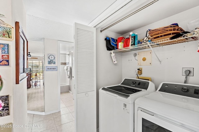 clothes washing area featuring laundry area, light tile patterned flooring, and washer and clothes dryer