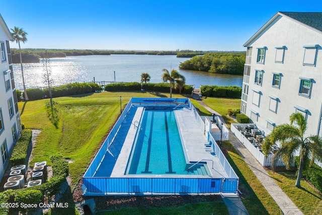 view of swimming pool with fence and a water view