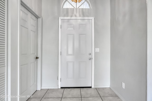 foyer entrance with light tile patterned floors and baseboards