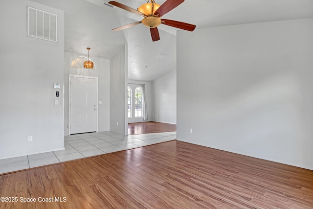 spare room featuring visible vents, lofted ceiling, a ceiling fan, and wood finished floors