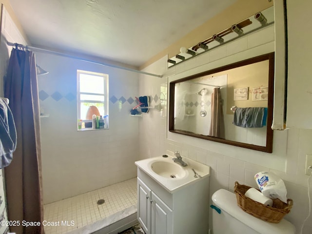 bathroom with a stall shower, tile walls, toilet, and vanity