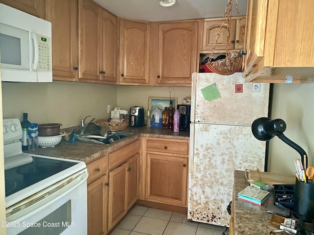 kitchen featuring white appliances, light tile patterned flooring, and a sink