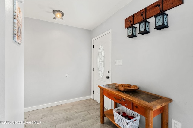 doorway featuring baseboards and light wood finished floors